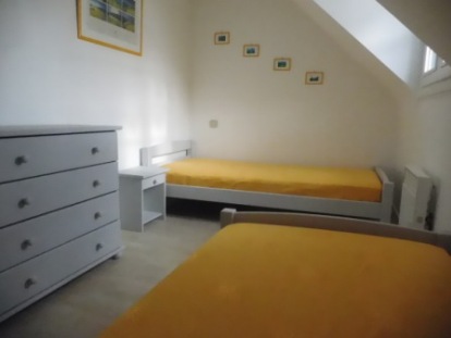 photo chambre jaune avec 2 lits d'une place.